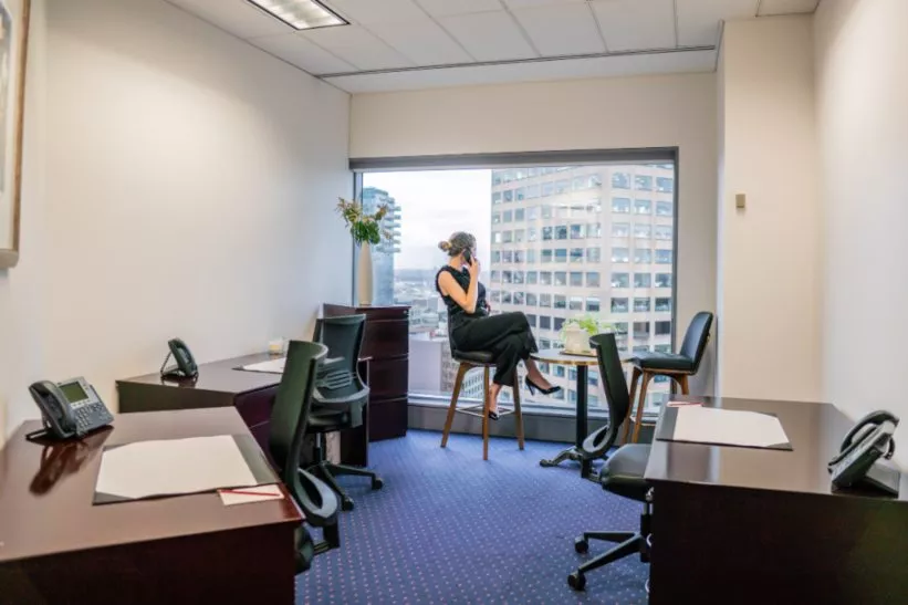 A woman in a serviced office at 10 Avenue Kléber, enjoying skyline views and a quiet, professional space to work and connect.